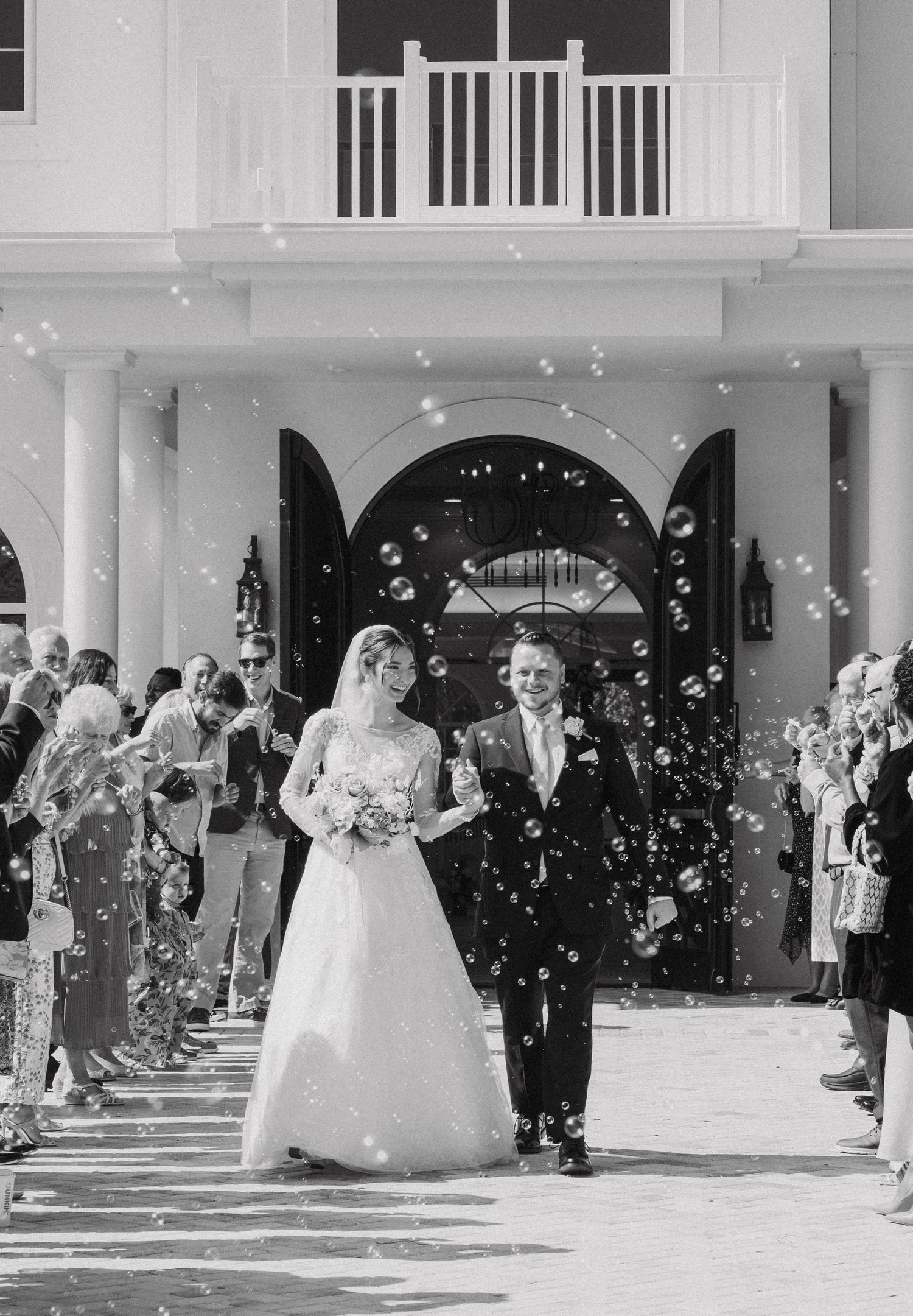 Wedding exit with guests throwing confetti outside a white columned building entrance.