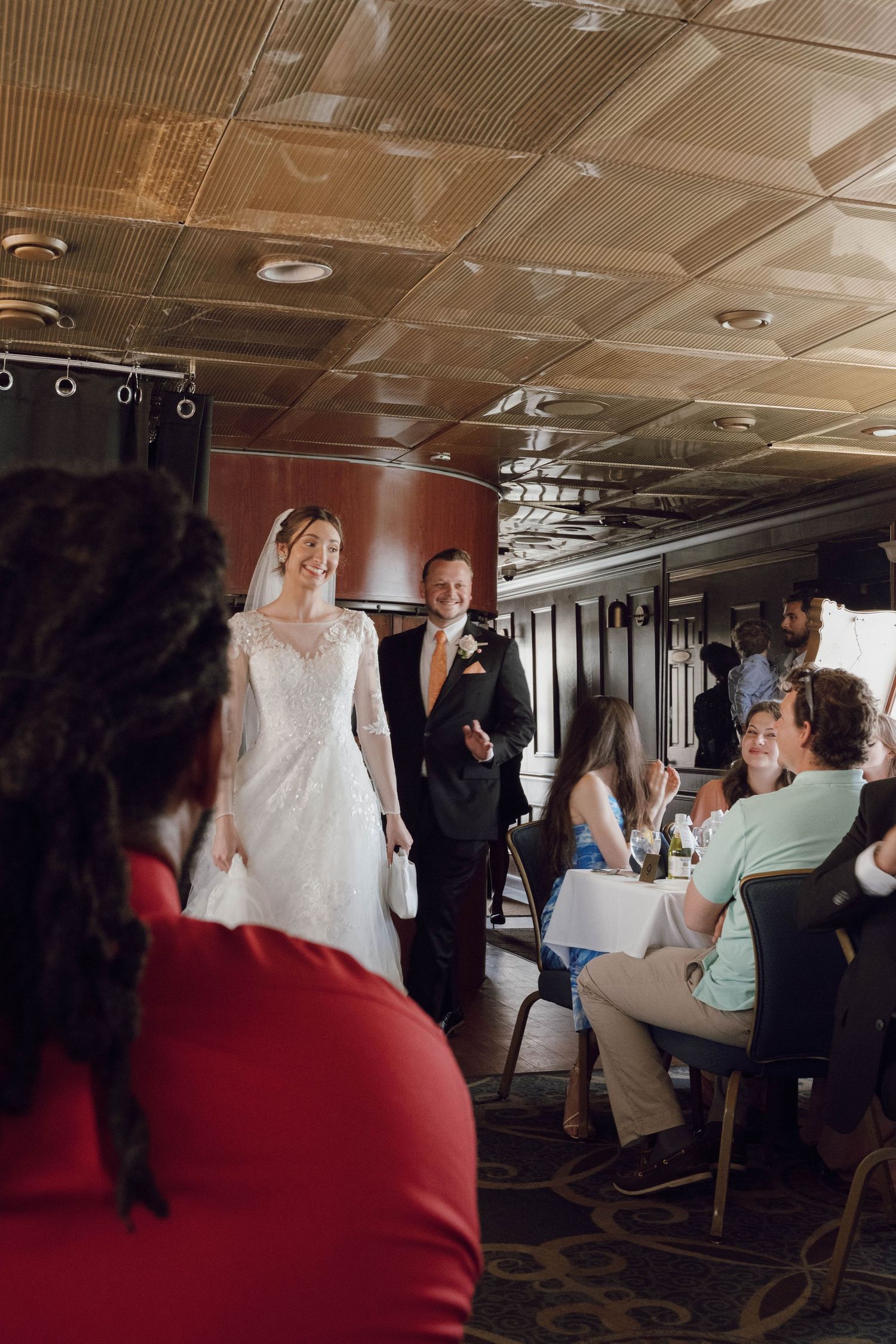 Wedding reception scene inside an elegant dining car with ornate ceiling and seated guests.