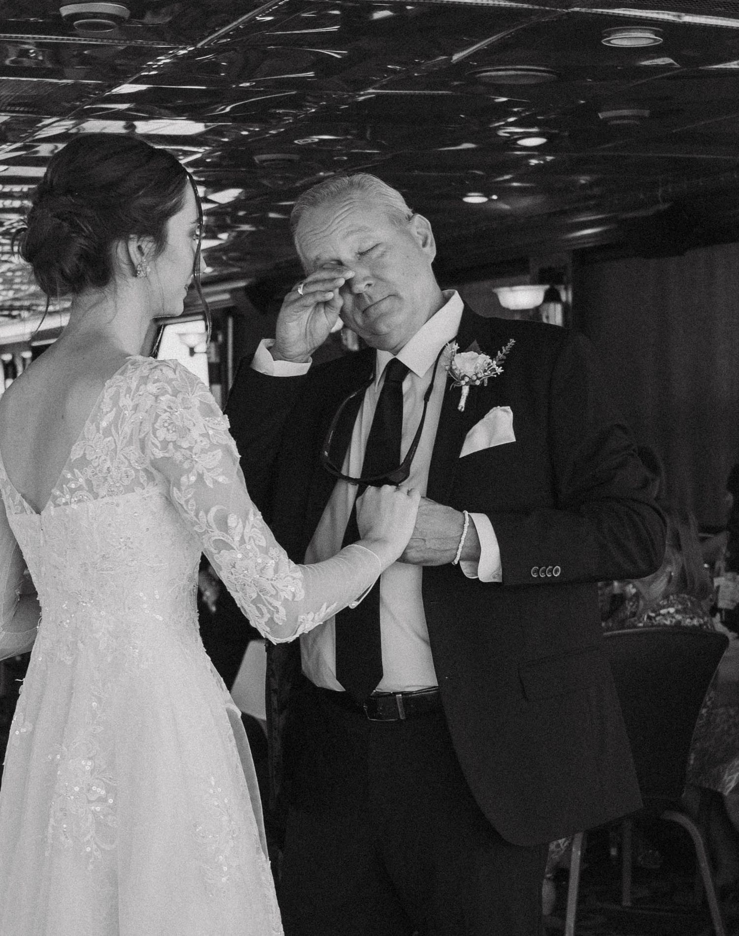 A couple dancing at a formal event in black and white, with the person in a white dress leading their dance partner.
