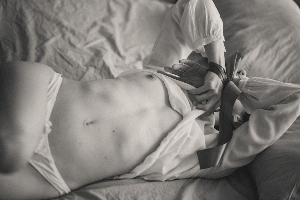 A series of black and white photos showing a sleeping baby nestled in soft white bedding.