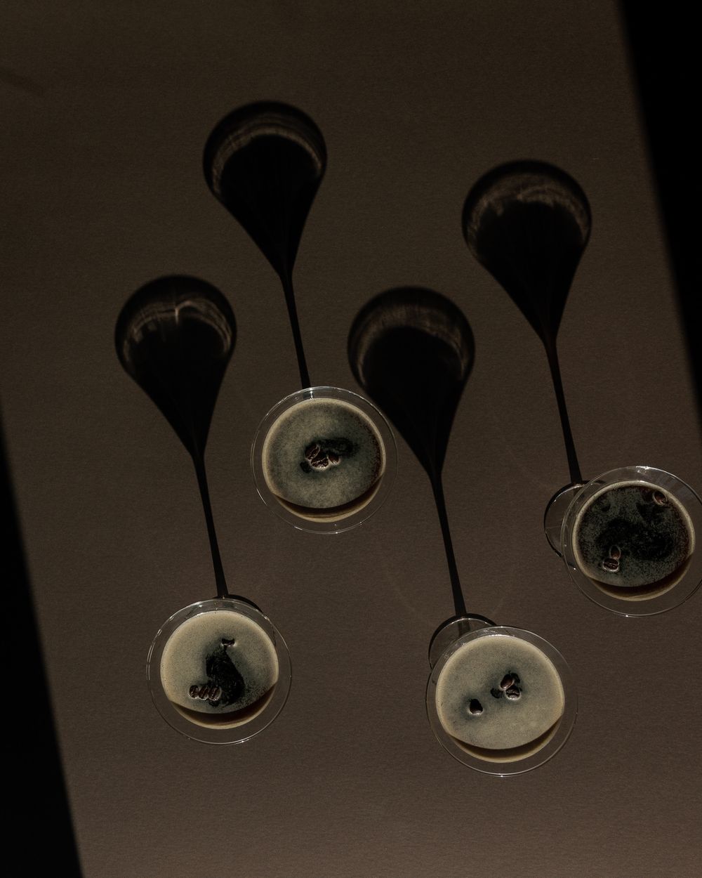 Artistic shadow composition of hanging glass pendant lights against dark background.