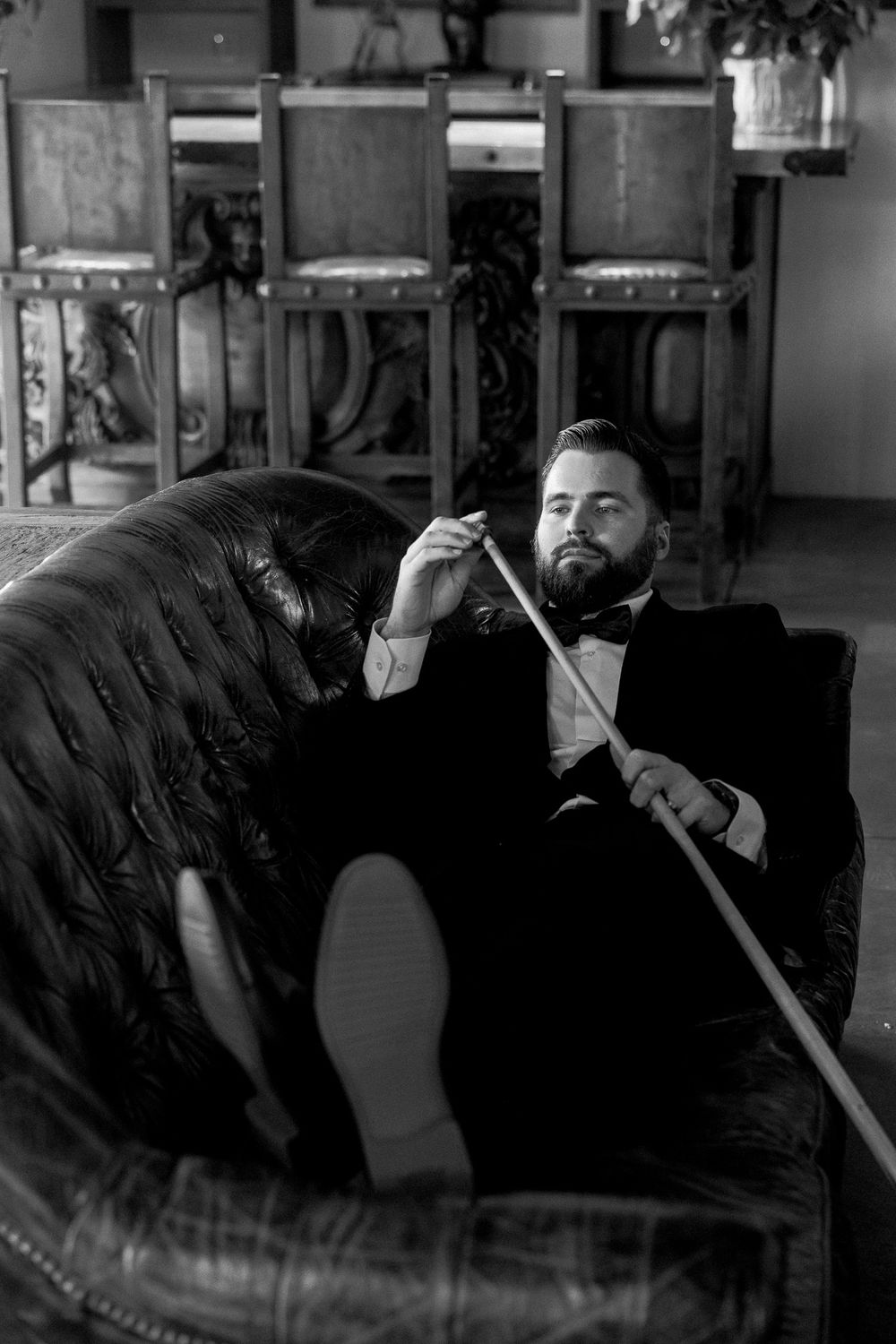 Black and white portrait of person reclining on vintage leather couch.