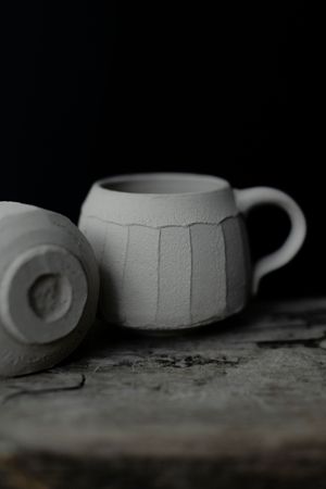 A series of black and white photographs showing different angles of a handmade ceramic mug with textured details.