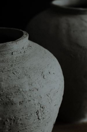 Close-up black and white photo sequence showing textural details of a ceramic vessel or pot against dark background.