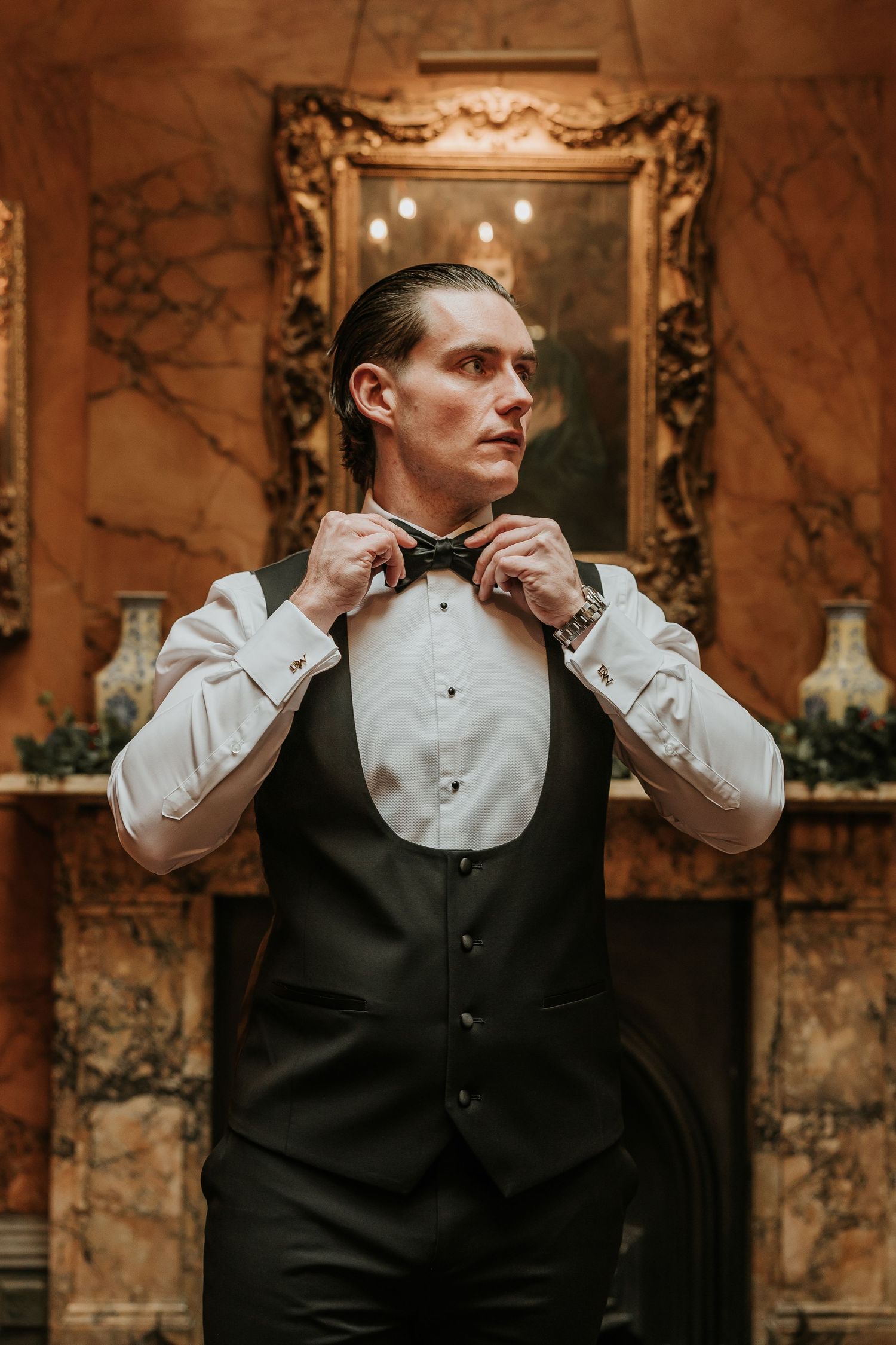A groom adjusts his black bow tie in a sequence of four elegant wedding preparation photos against marble walls.