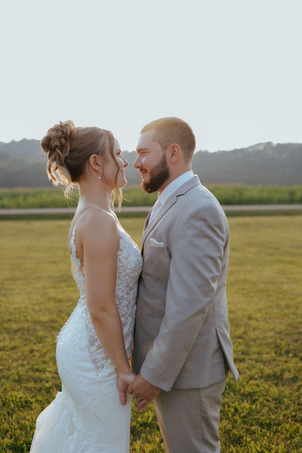 Newlywed couple shares romantic moments in a golden sunlit field at sunset.