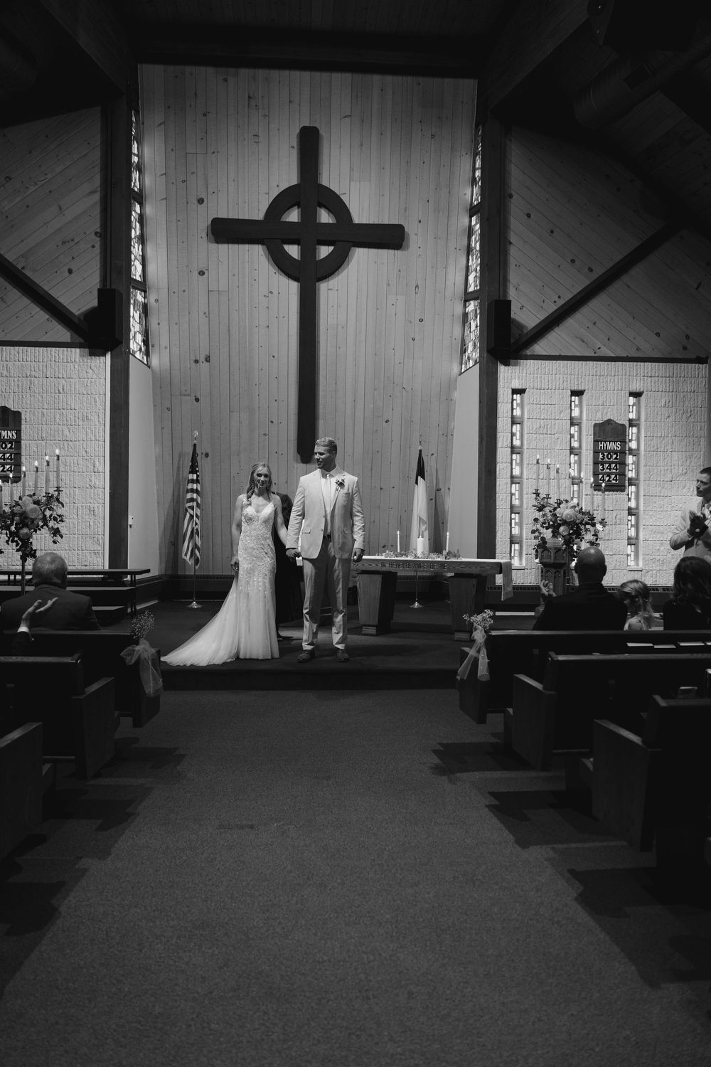 Black and white photos show a wedding ceremony sequence in a church with a large cross on the altar.