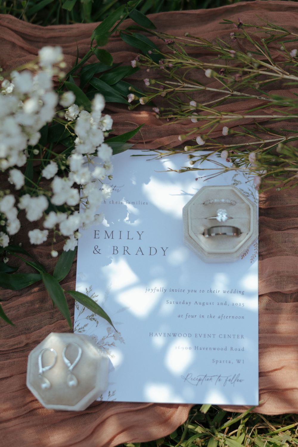 Wedding invitation cards with delicate white flowers and dappled sunlight creating an elegant, romantic composition.