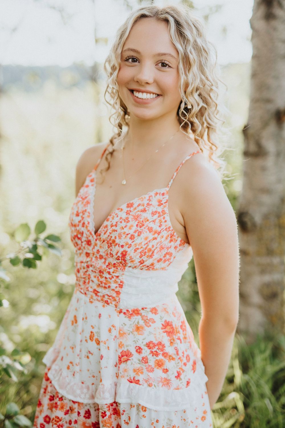 A summer dress with coral floral patterns and white lace details captured in natural outdoor lighting.
