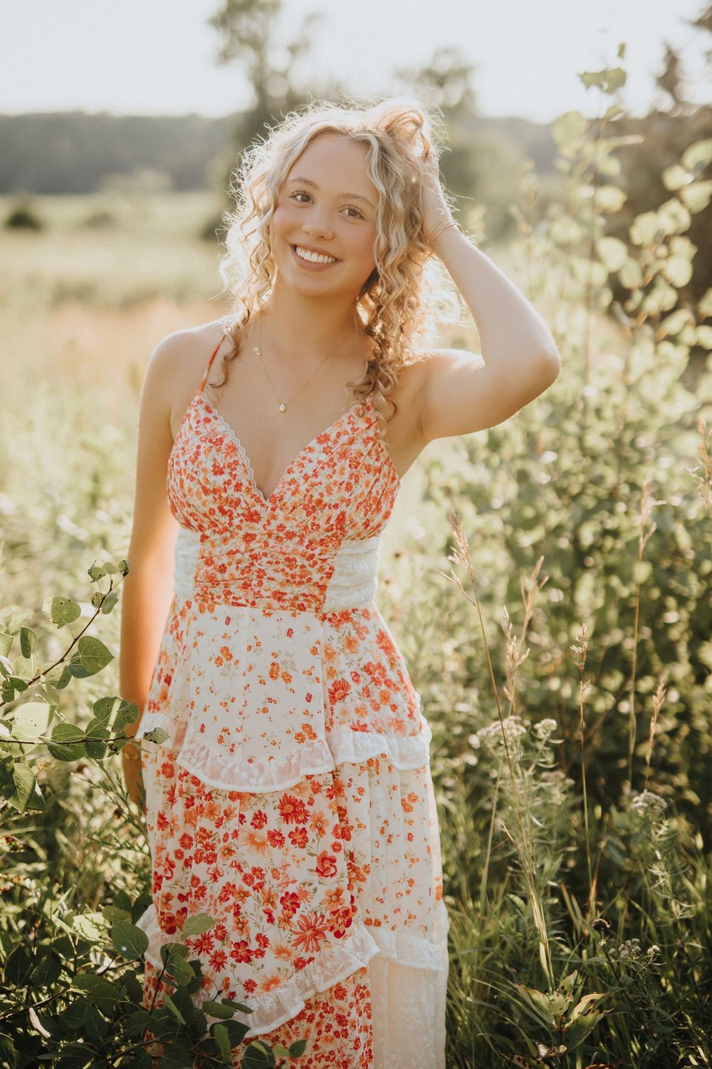 A white and coral floral dress stands out beautifully against lush summer foliage in warm sunlight.