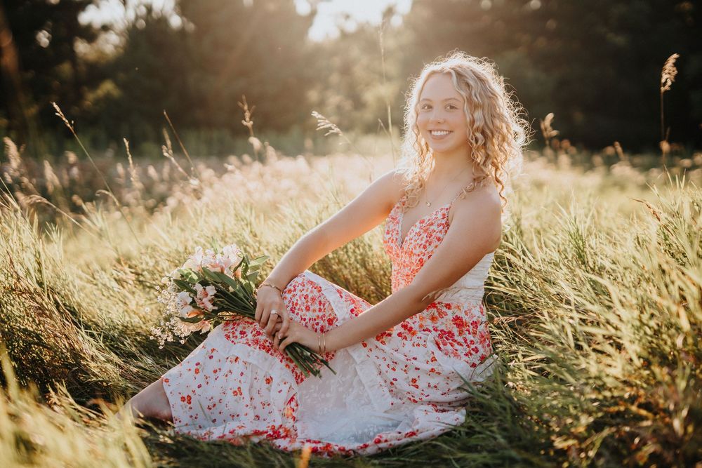 A floral dress flows gracefully in a golden sunlit meadow during a dreamy summer photoshoot.