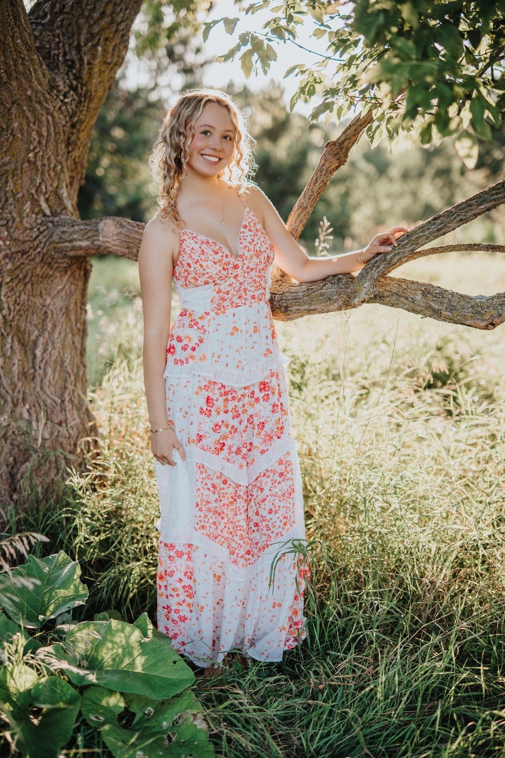A floral print sundress is captured in a series of outdoor photos under a tree in warm sunlight.