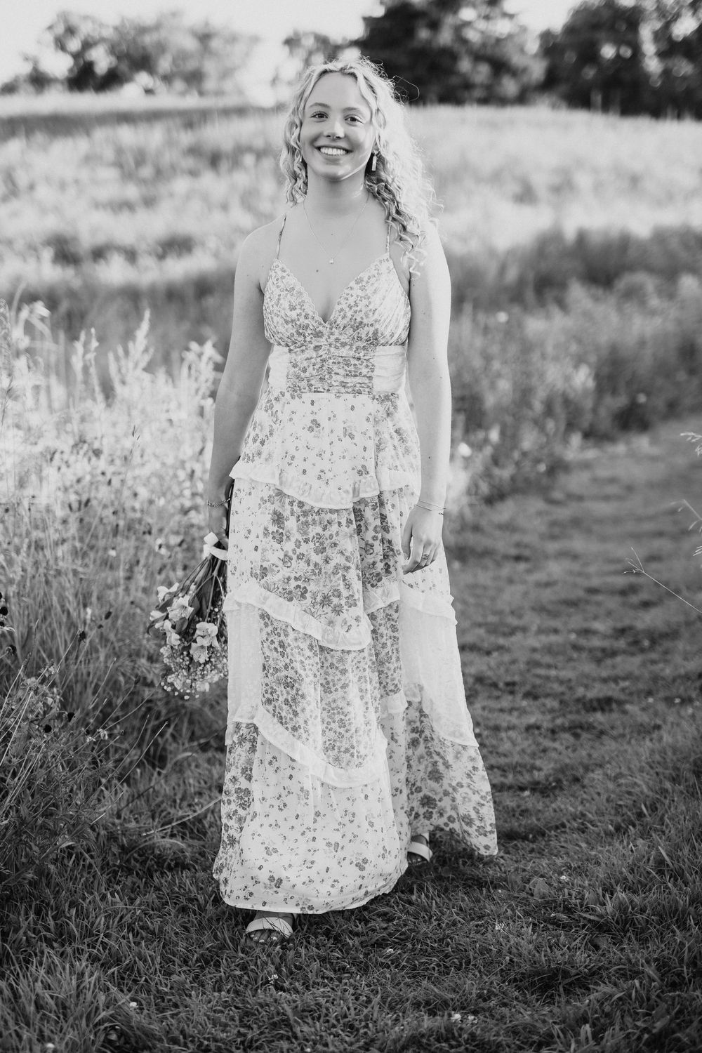 Black and white portraits showcase a floral dress in a natural outdoor setting with tall grass.