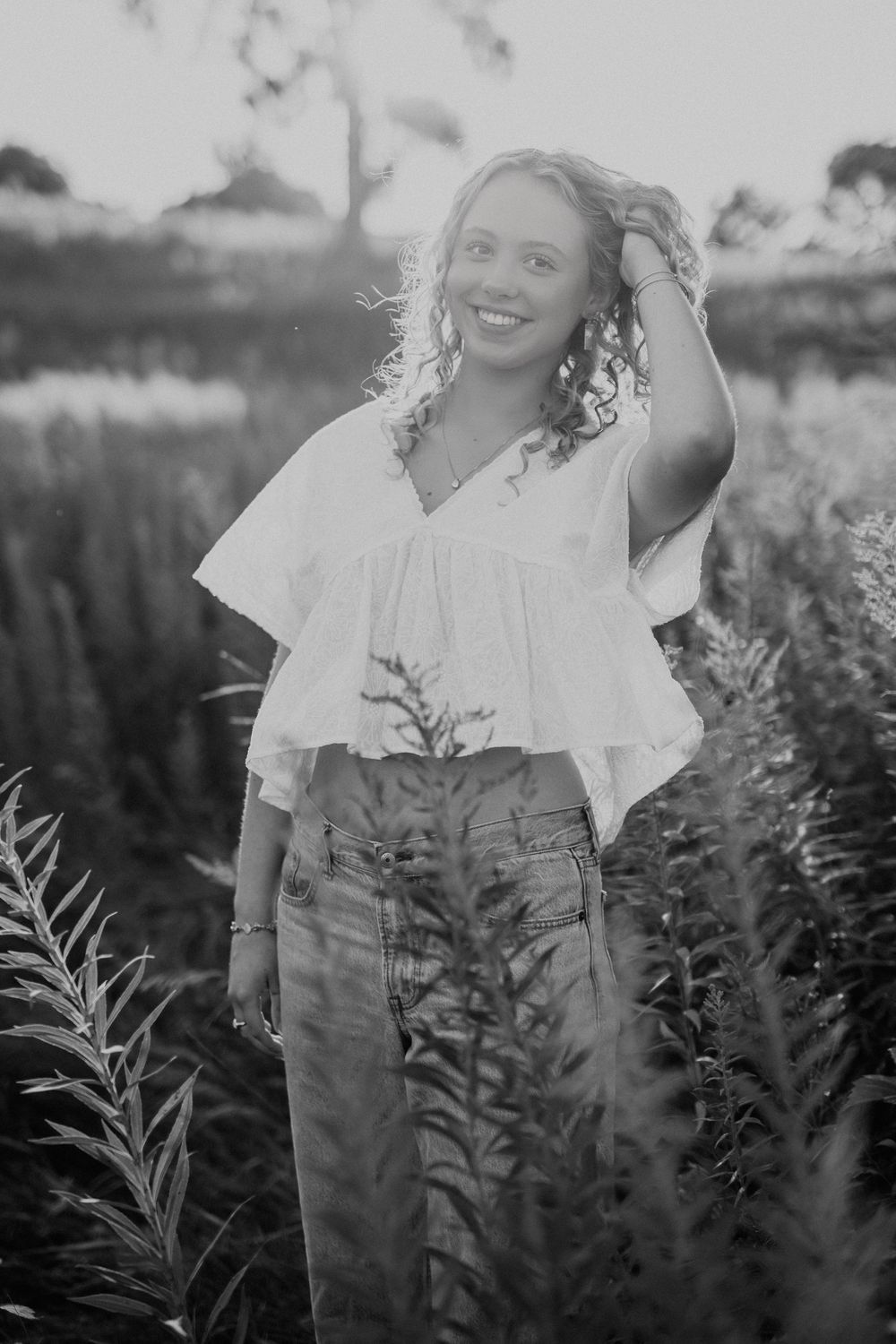 Black and white portrait showing a playful summer moment among wildflowers and natural scenery.