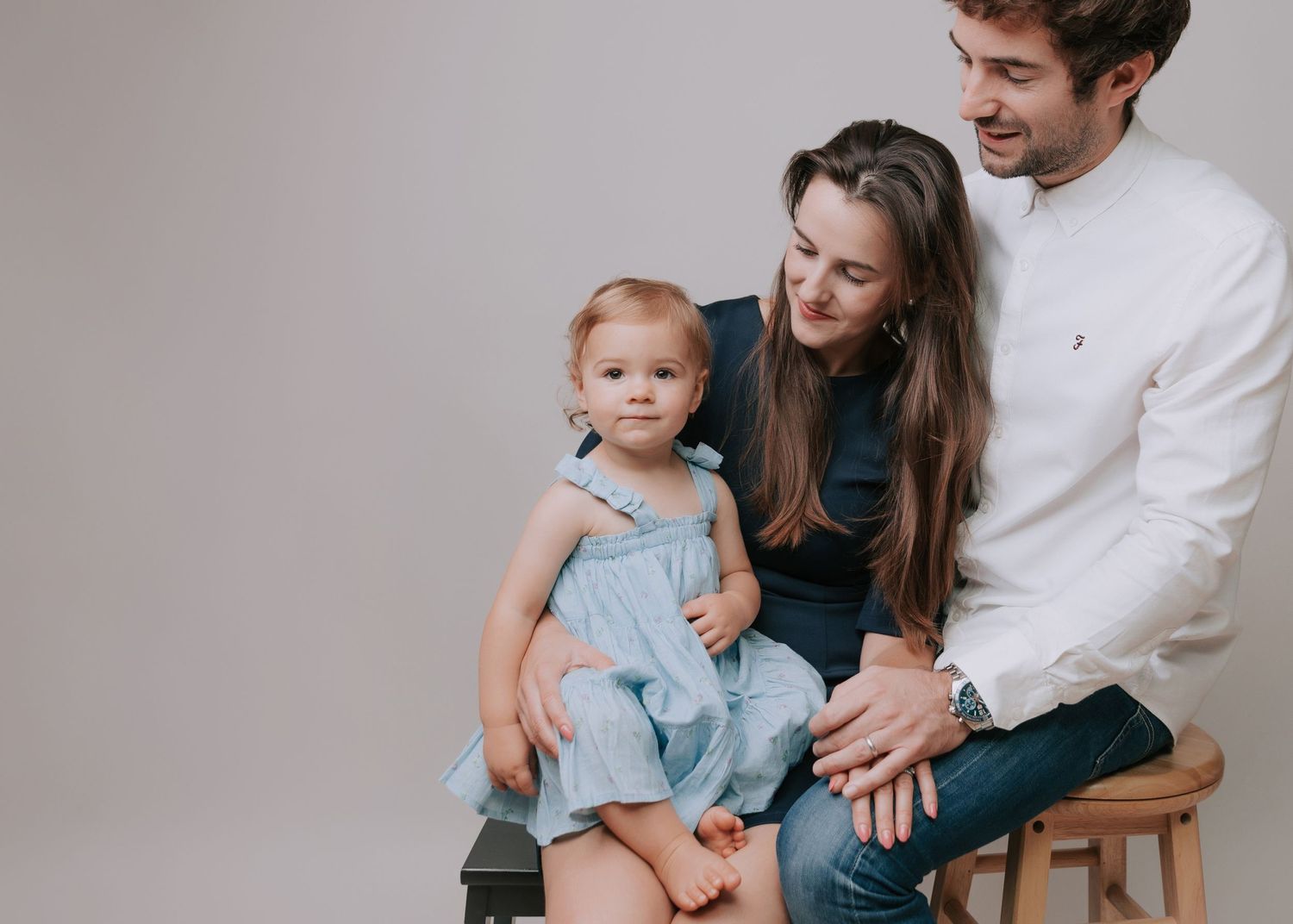 family of 3 interacting, daughter looking at camera dressed in shades of blue in studio backdrop