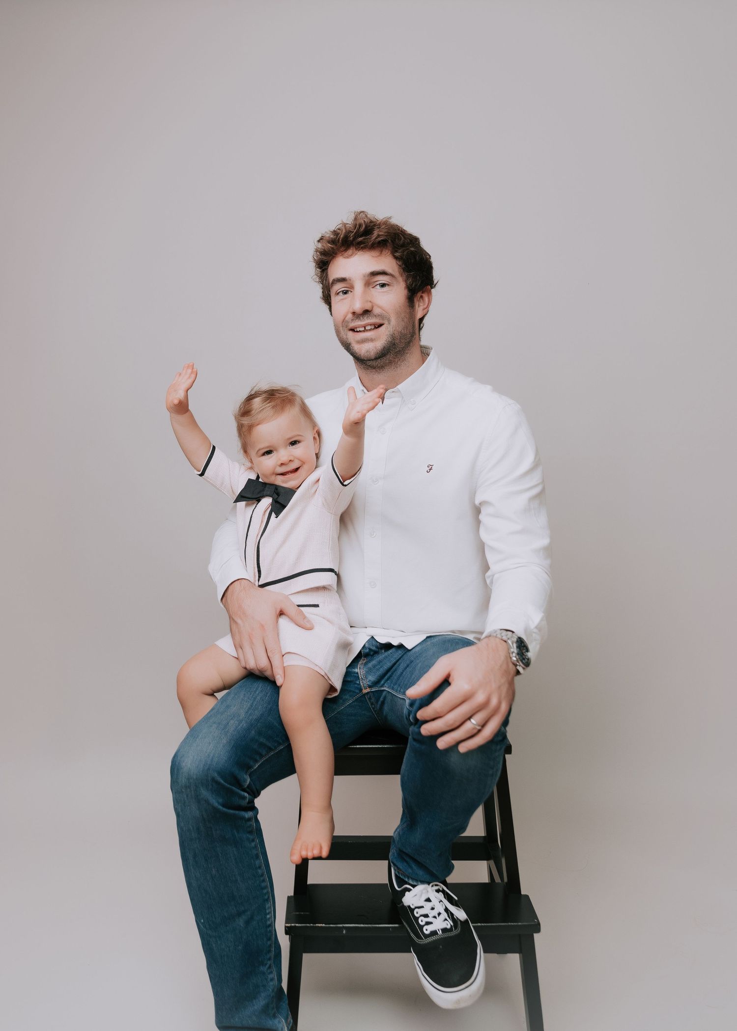 Father and daughter smiling at camera dressed in shades of blue and white in studio backdrop