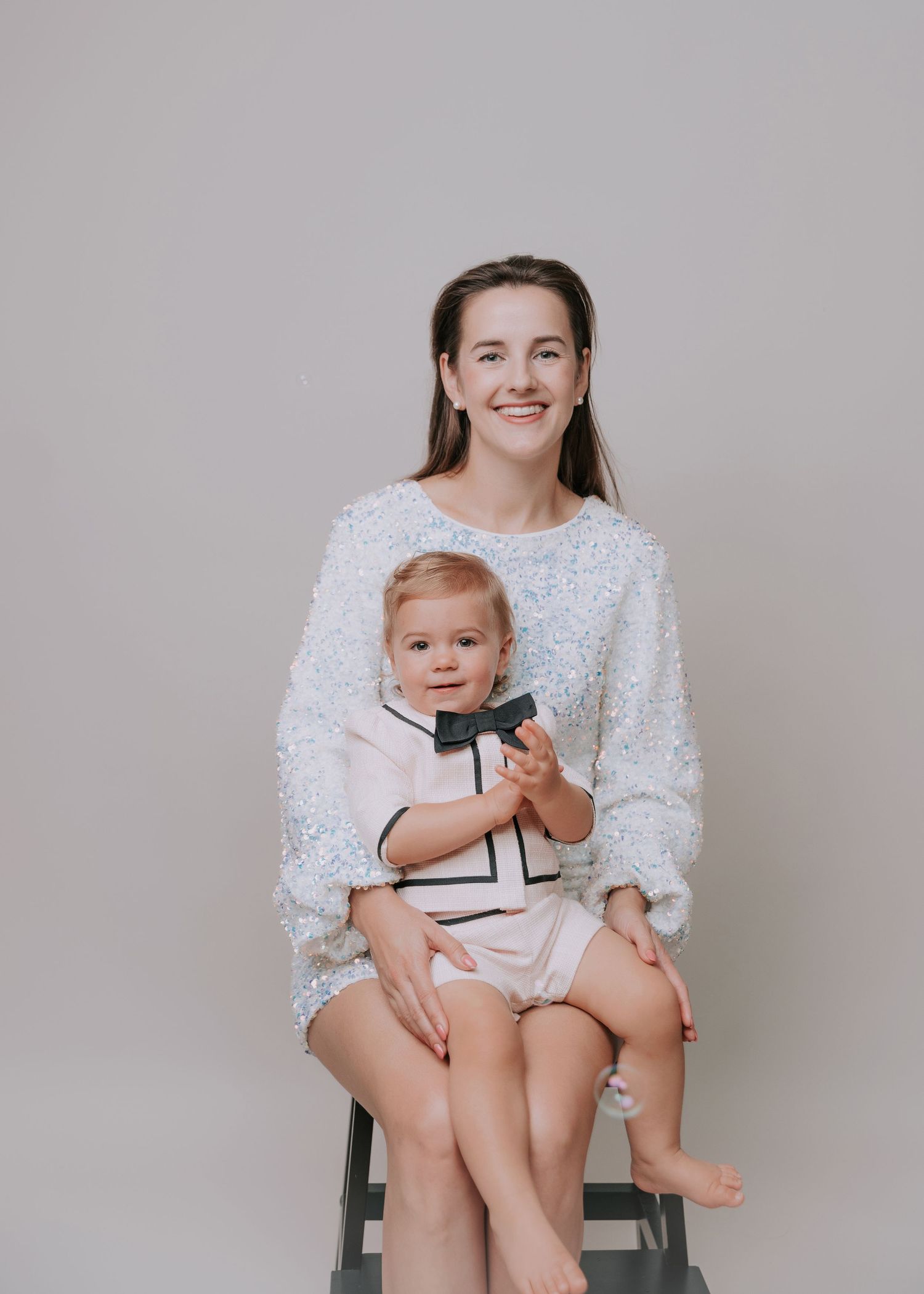 Mother and daughter smiling at camera dressed in shade of white in studio backdrop