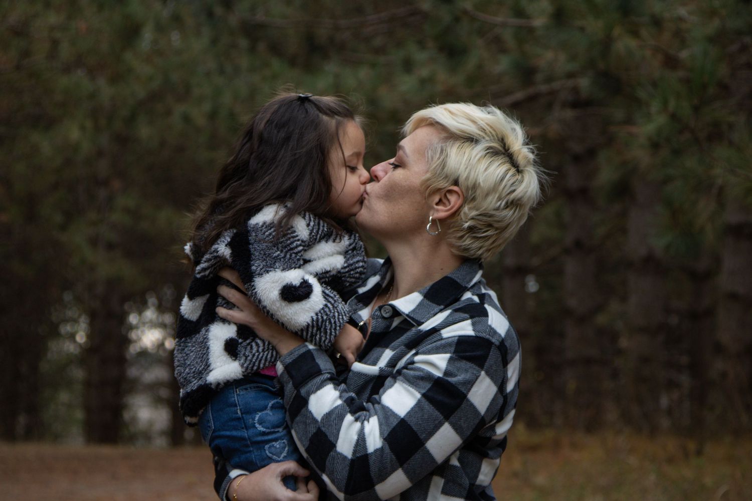 Two people in buffalo plaid share a tender moment outdoors.