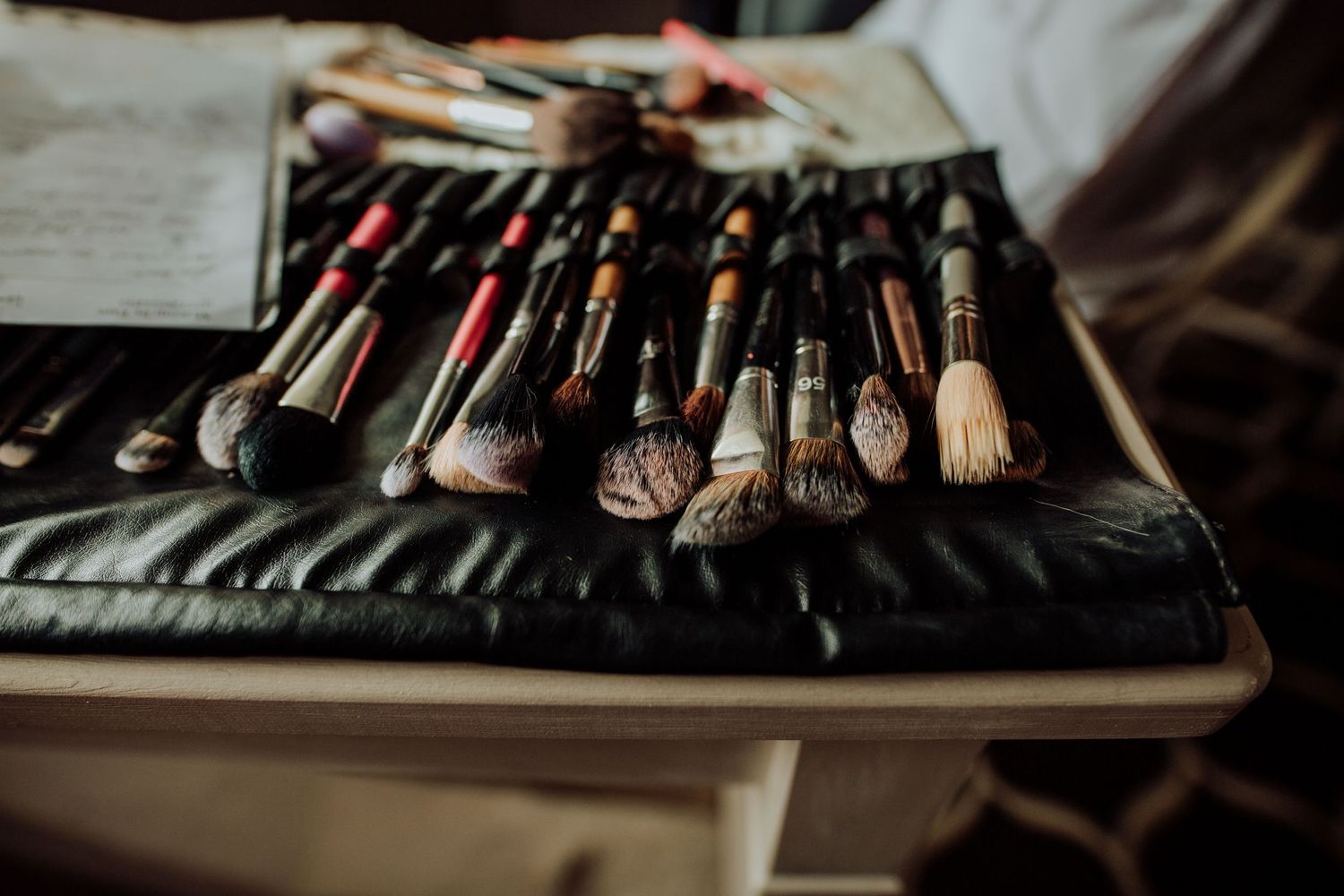 Professional makeup brushes arranged on a black leather case for bridal beauty preparation.