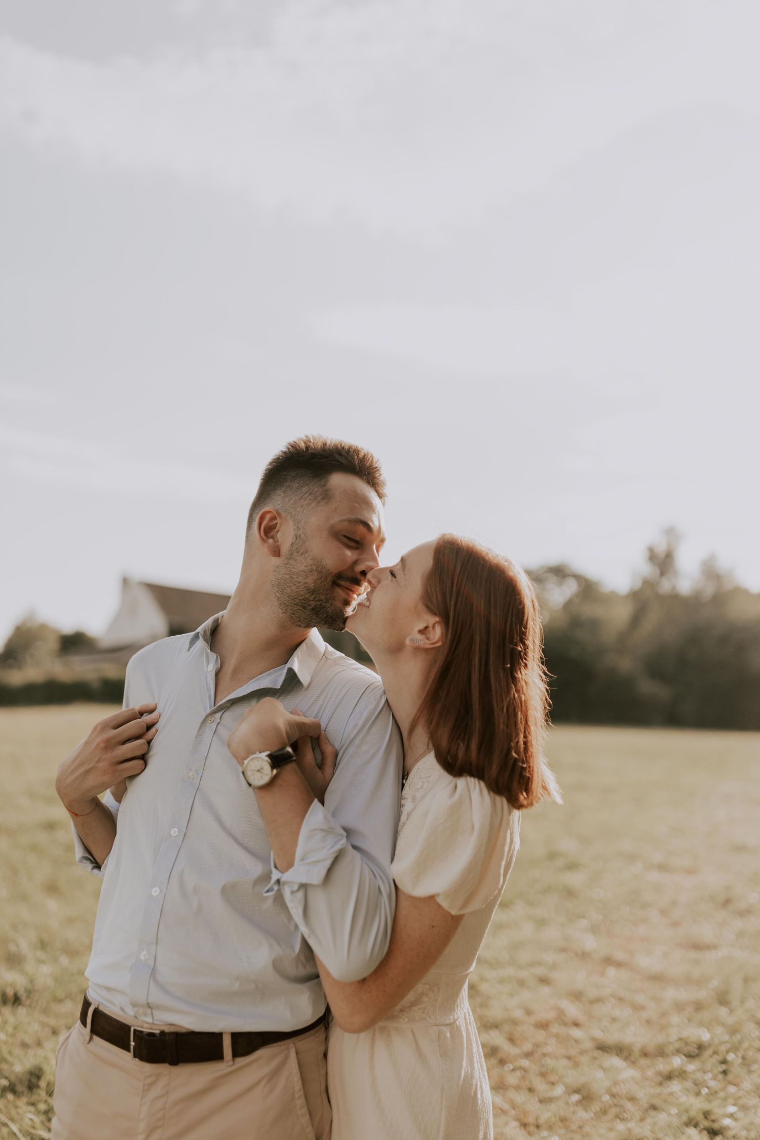 Un couple partage un moment intime dans un champ doré lors d'une séance photo au coucher du soleil.