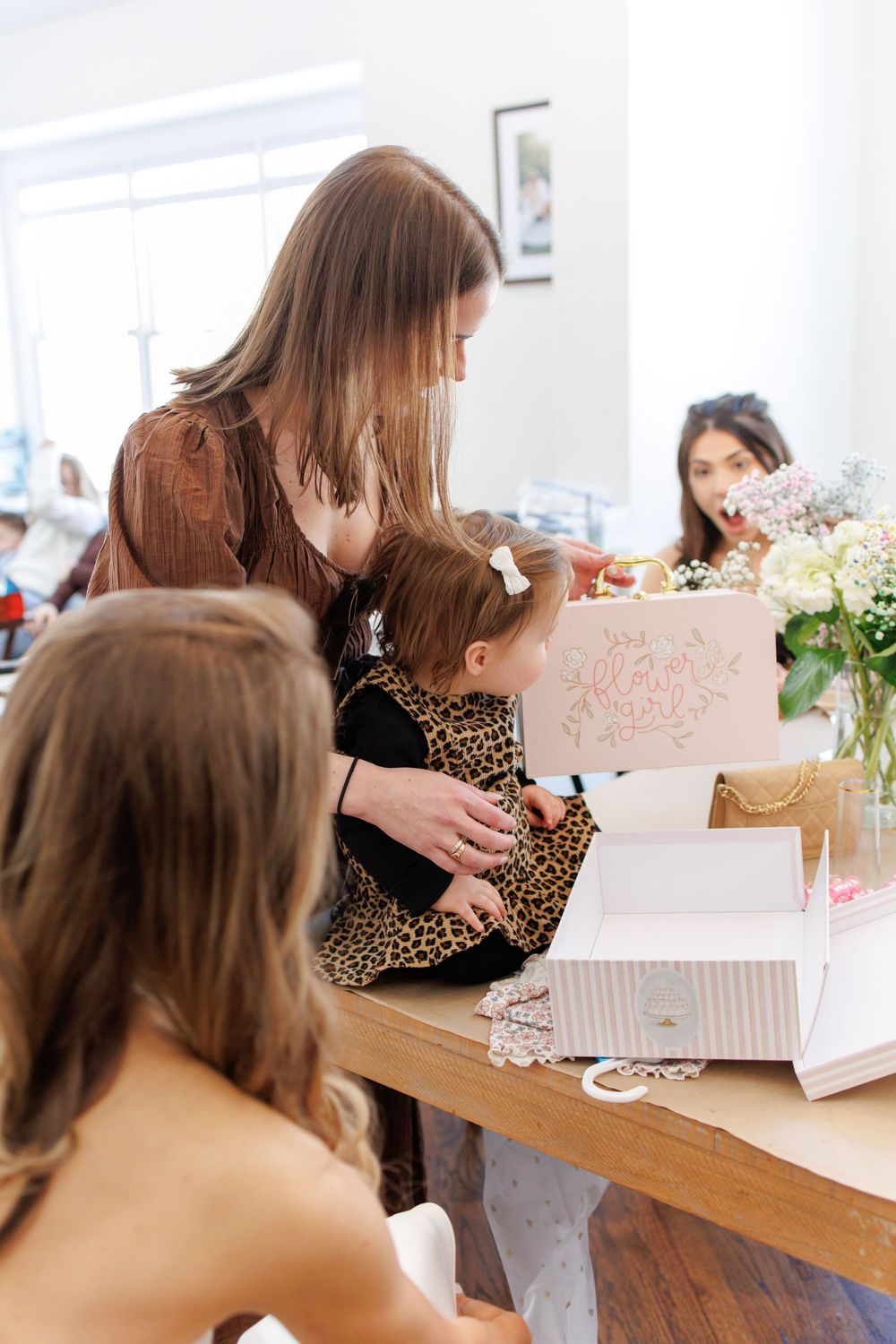 Women sit at a wooden table looking through white paper documents and folders in an office setting.