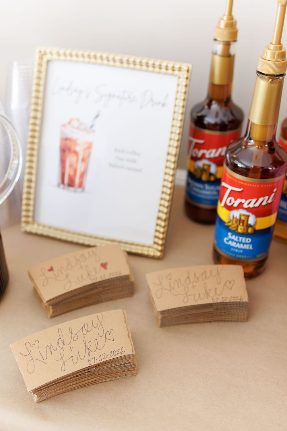 Brown kraft paper name cards with handwritten text sit on a table with syrup bottles in the background.