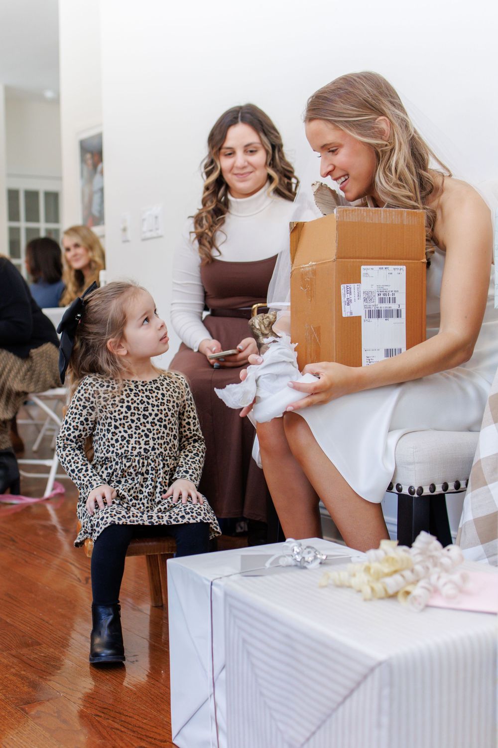 A series of four photos showing a child and adult opening gifts at a baby shower celebration.