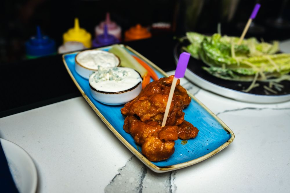 Appetizer plates with golden fried snacks, dipping sauces, and fresh vegetables arranged on a dark table.
