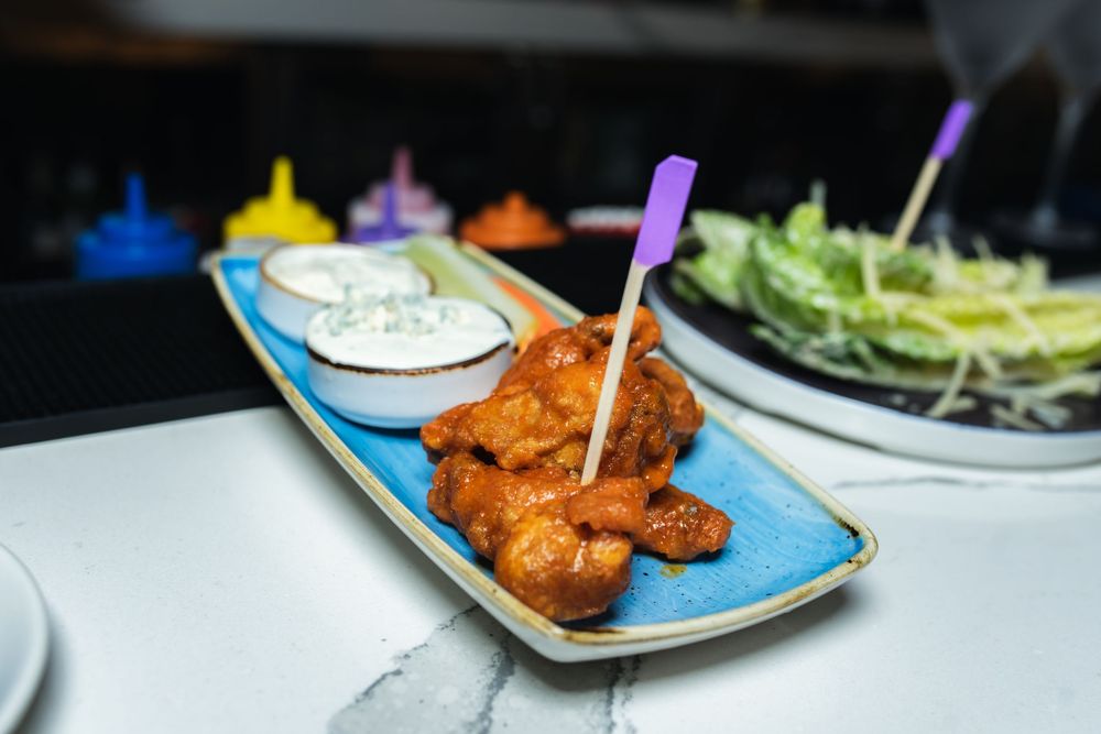 A plate of golden fried chicken nuggets or popcorn chicken served on a light blue rectangular platter with toothpicks.