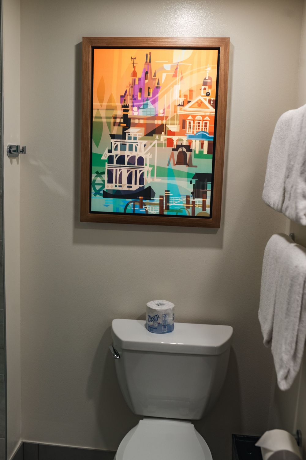 Colorful framed artwork featuring vibrant cityscapes decorates the walls of a modern bathroom interior.