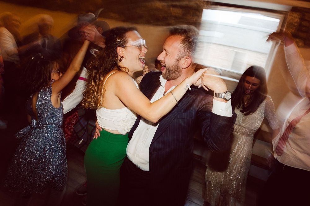 Party guests dancing and enjoying themselves at a dimly lit indoor celebration.