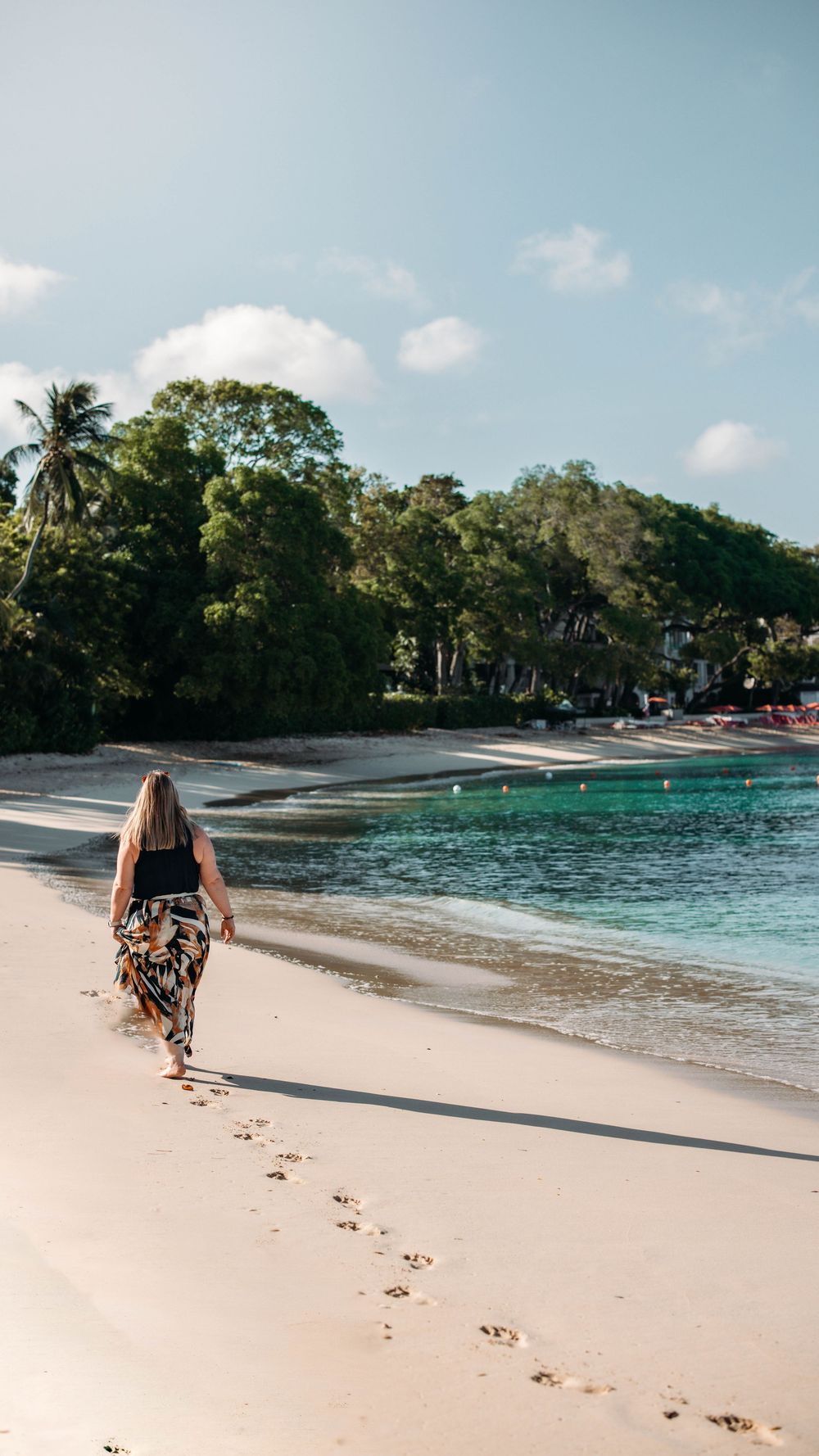 Pristine white sand beach with turquoise waters and palm trees under blue skies.