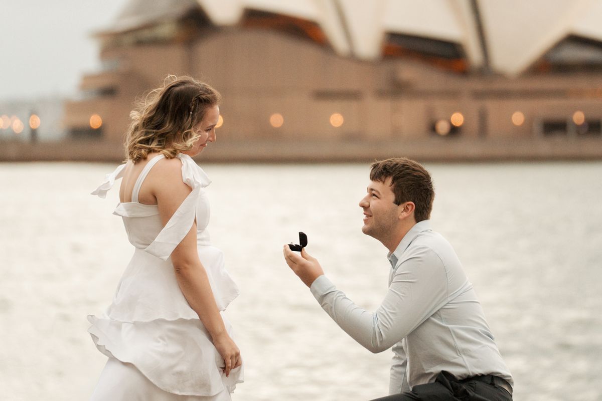 A romantic proposal scene with the Opera house in the background in sydney the Rocks photoshoot
