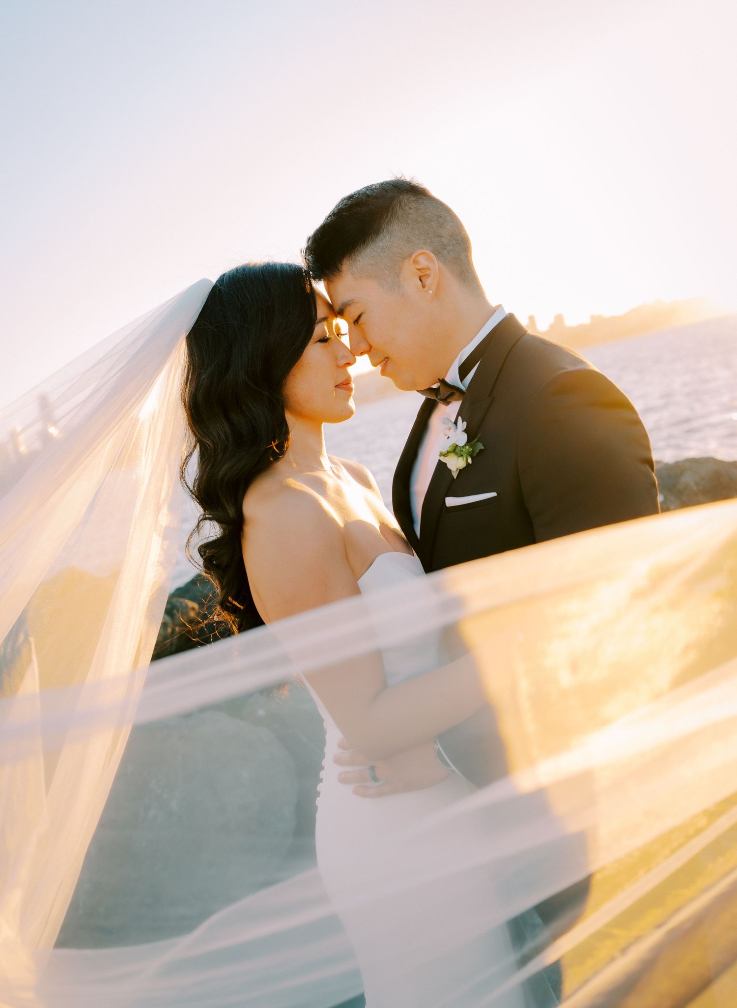 Romantic sunlit moment with flowing veil creating ethereal atmosphere.