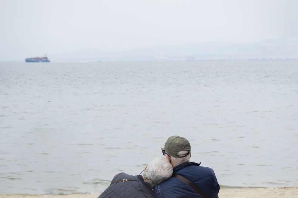 A scenic coastal landscape with misty gray skies over calm waters stretches to the horizon.