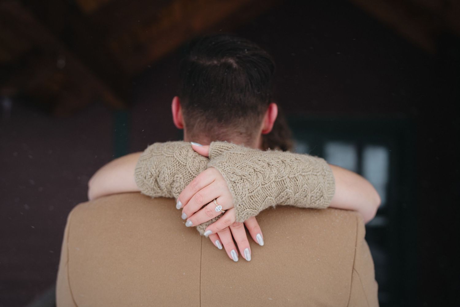 A close-up shot shows hands embracing on a tan coat during an intimate moment.