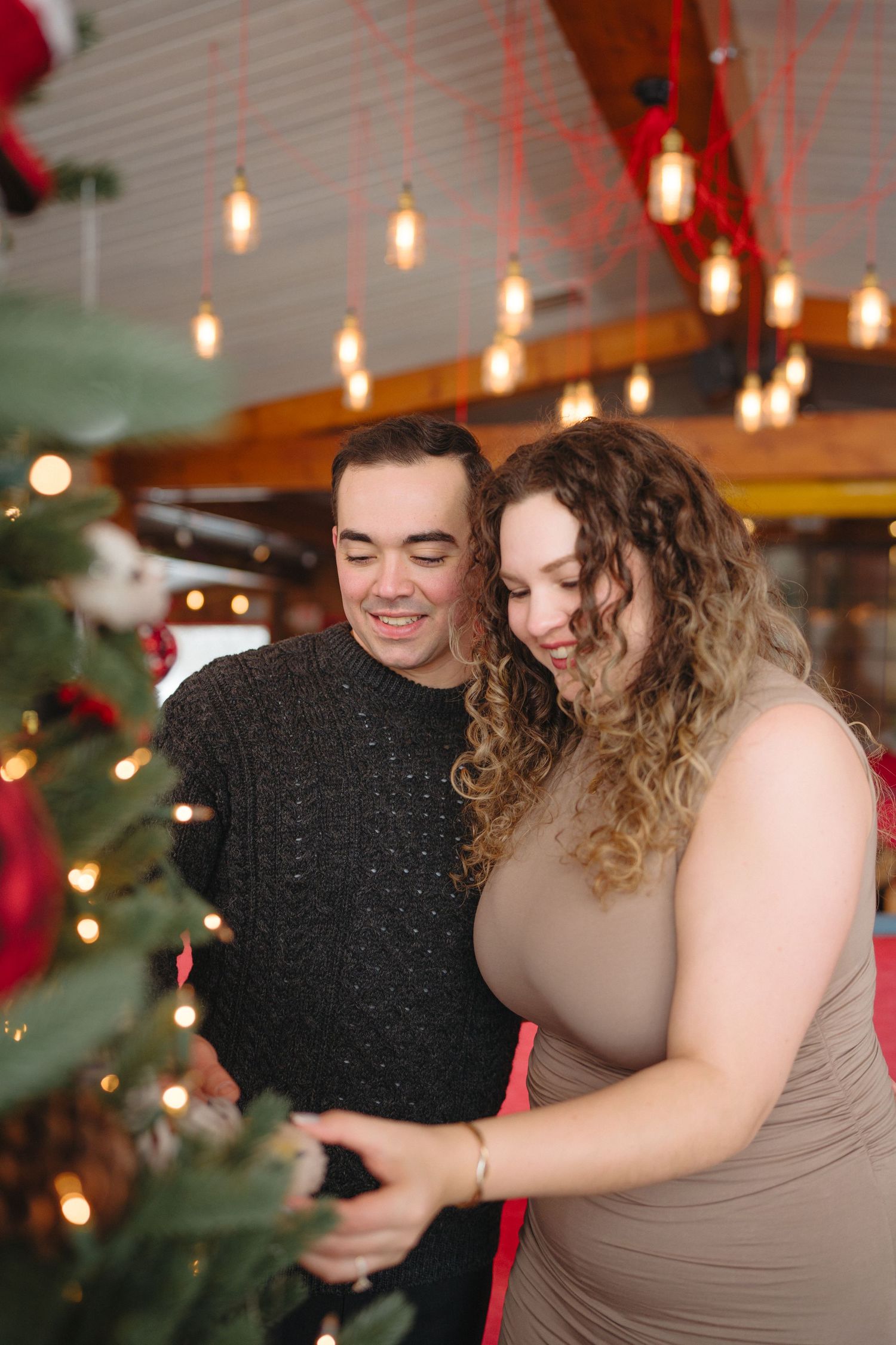 A cozy indoor holiday scene with string lights and decorations as a couple embraces.