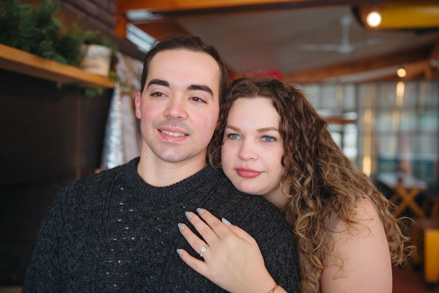 A couple shares an intimate moment under warm lighting with festive decorations in the background.