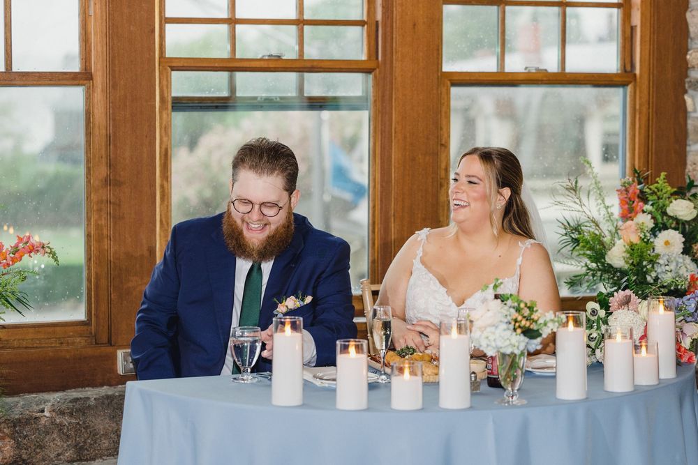 Wedding reception head table with candles and floral centerpieces in a rustic wooden lodge venue.