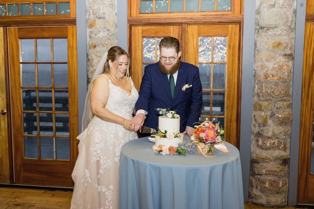 Elegant wedding table settings with blue linens and floral centerpieces against rustic stone walls and windows.