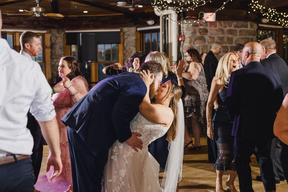 Wedding celebration in a rustic stone venue with string lights and wooden beams overhead.