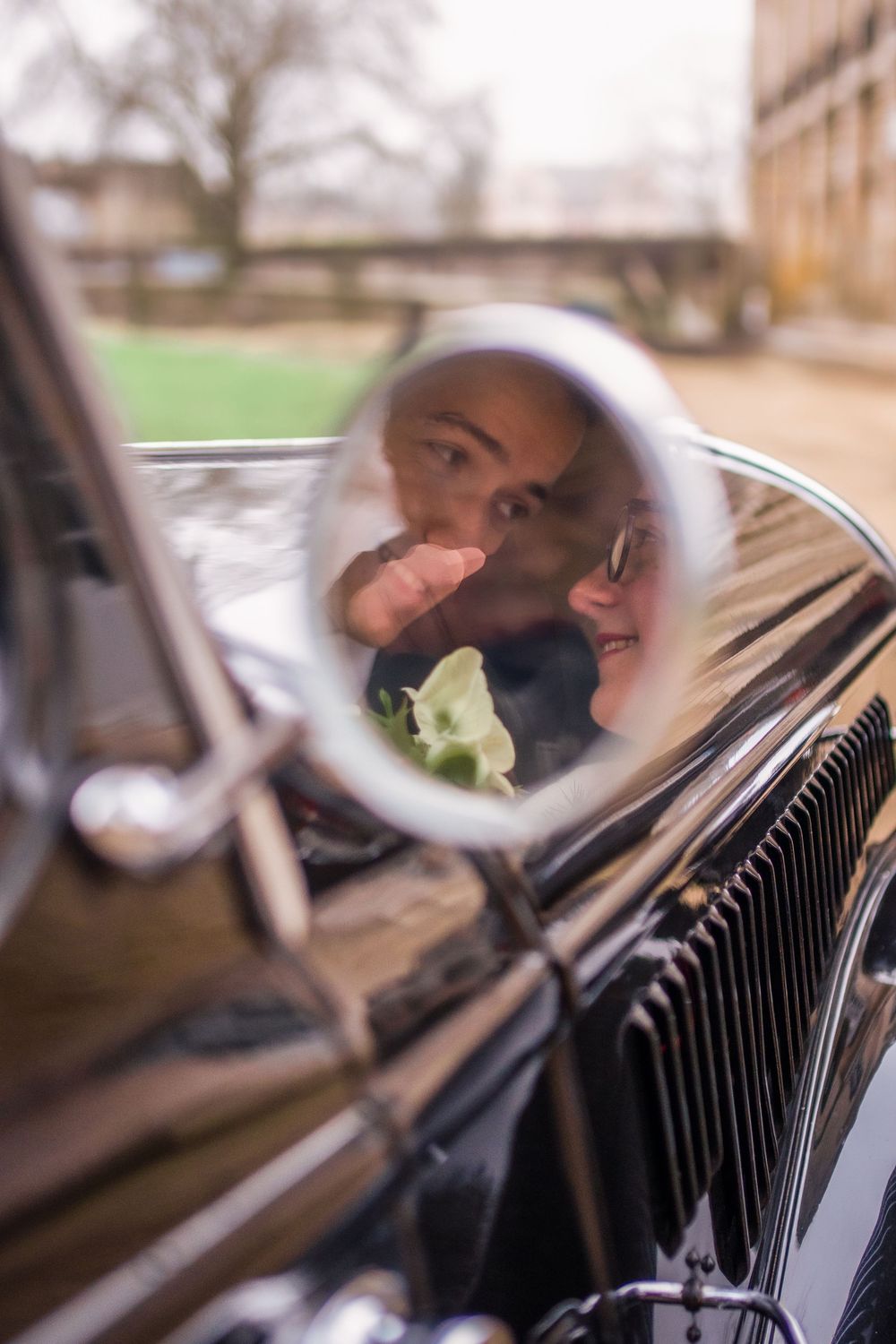 Des mariés dans le reflet du rétroviseur d'une veille voiture