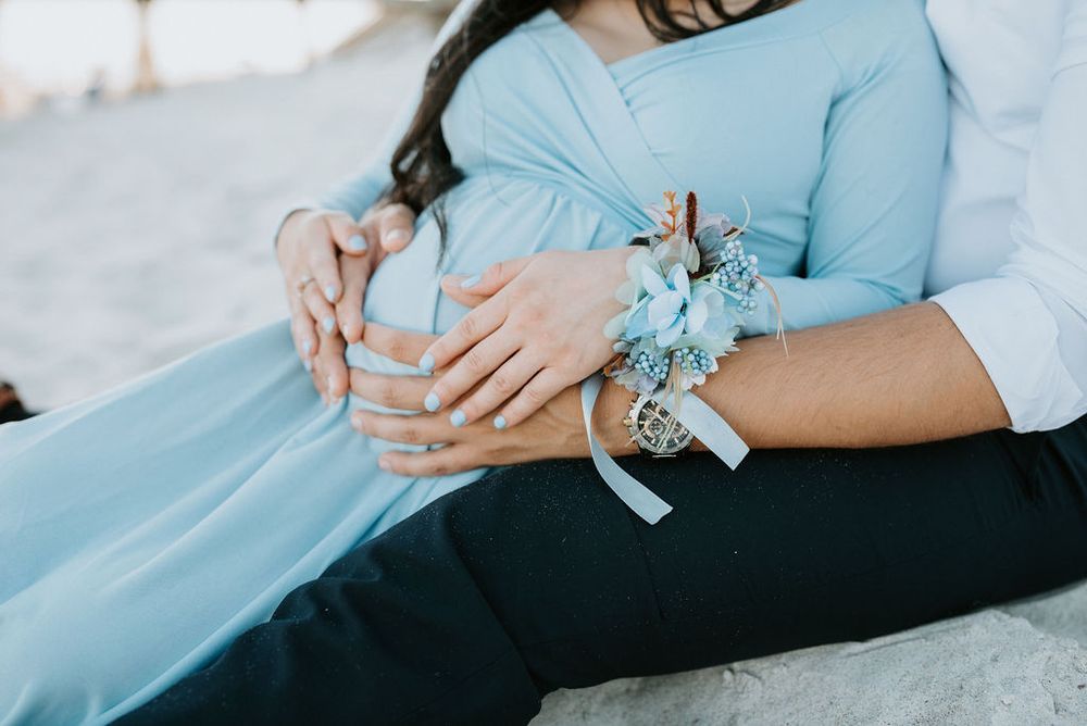 Close-up details of a couple's hands and light blue dress fabric during an intimate engagement photo session.