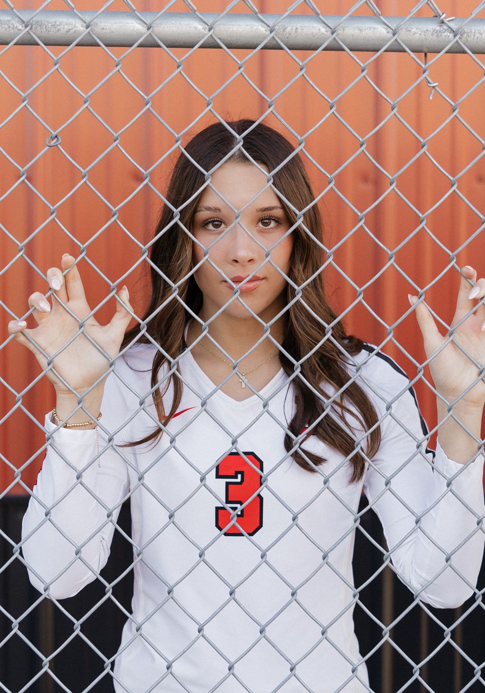 A series of photos showing someone in a white shirt posing behind a chain link fence against an orange background.