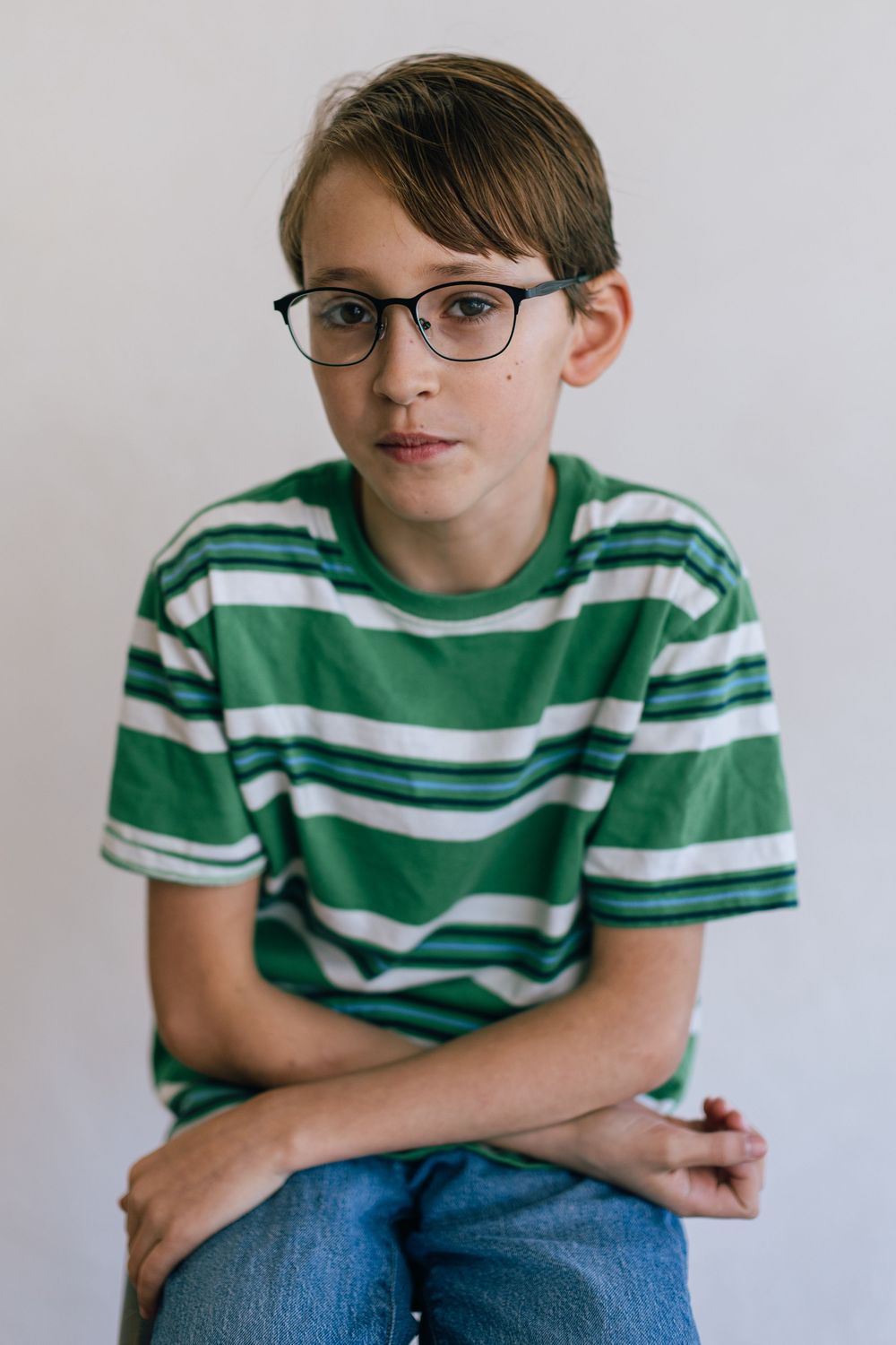 A series of four photos showing someone wearing glasses and a green striped shirt sitting against a white background.