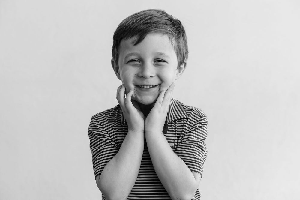 A black and white photo series showing joyful expressions and playful poses in a striped shirt.