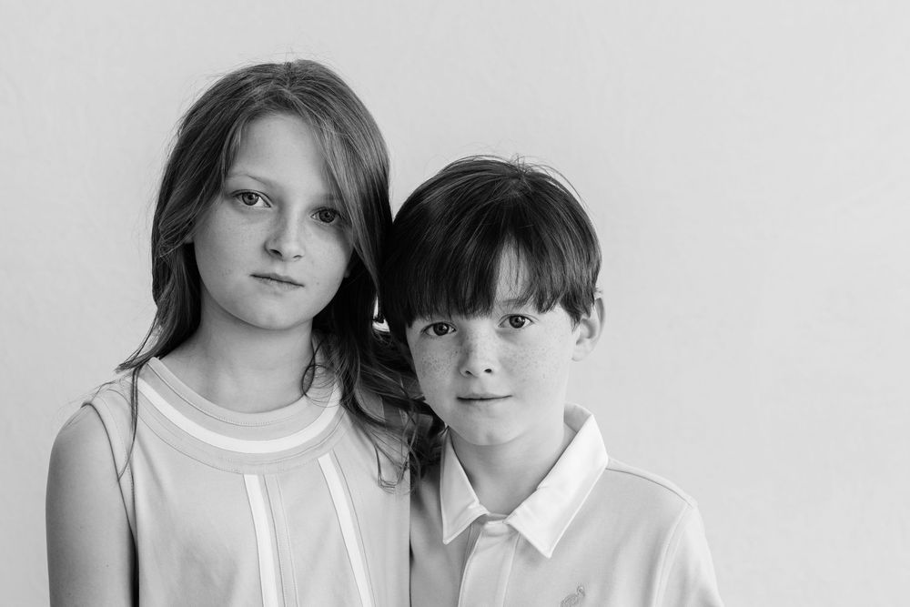 Black and white portrait photo series showing four similar poses in a minimalist studio setting.