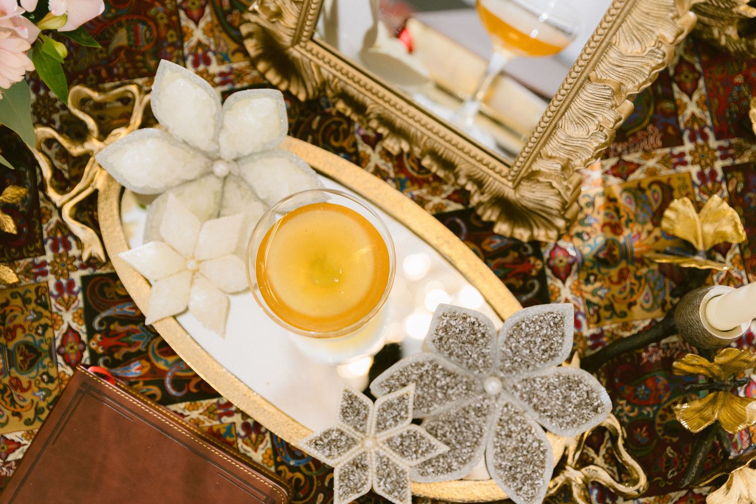 Overhead view of a floral arrangement featuring peach roses, white flowers, and golden decorative elements on a dark surface.