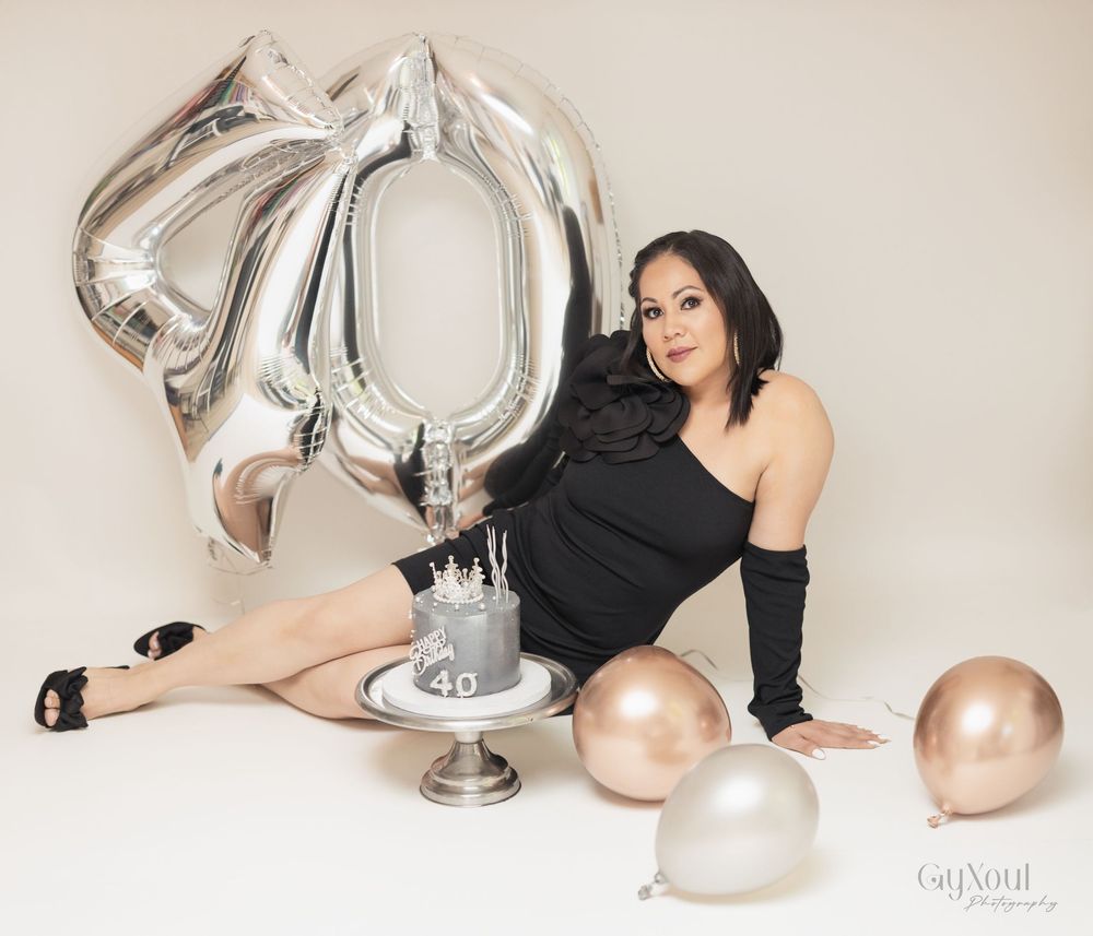 Elegant celebration setup with silver number 70 balloon, champagne glass, and rose gold balloons on beige background.