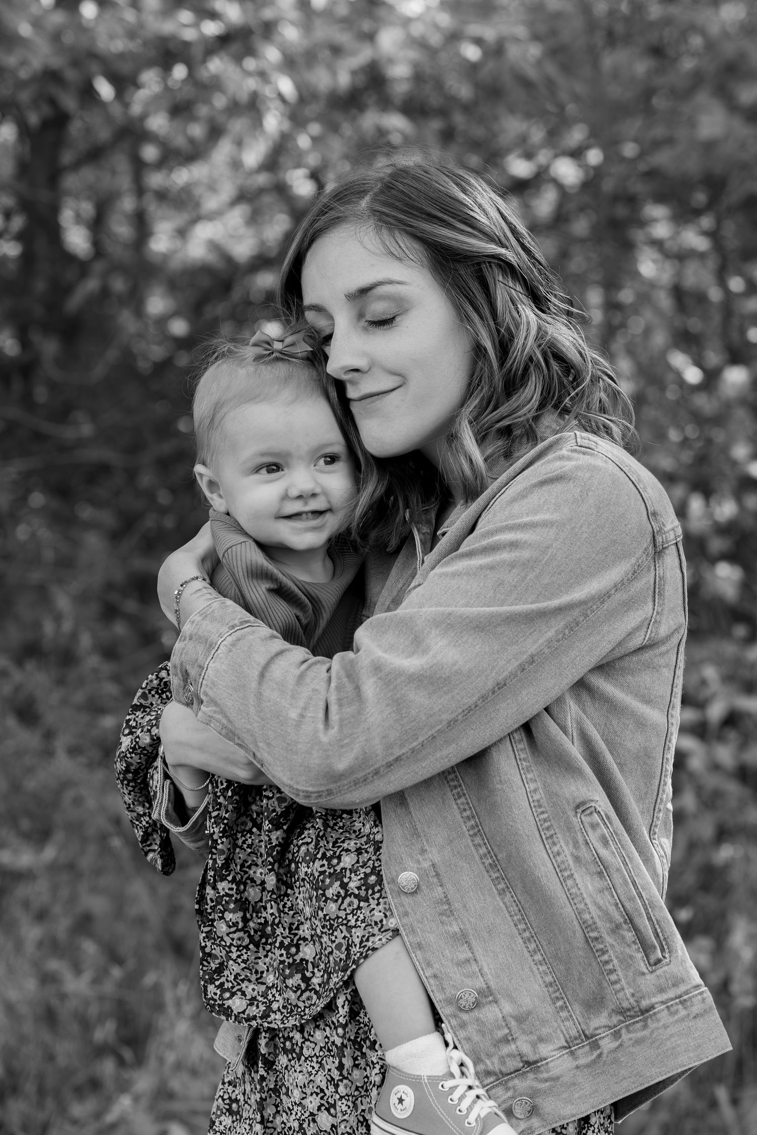 A heartwarming black and white photo series showing tender moments between a parent and child in a wooded setting.